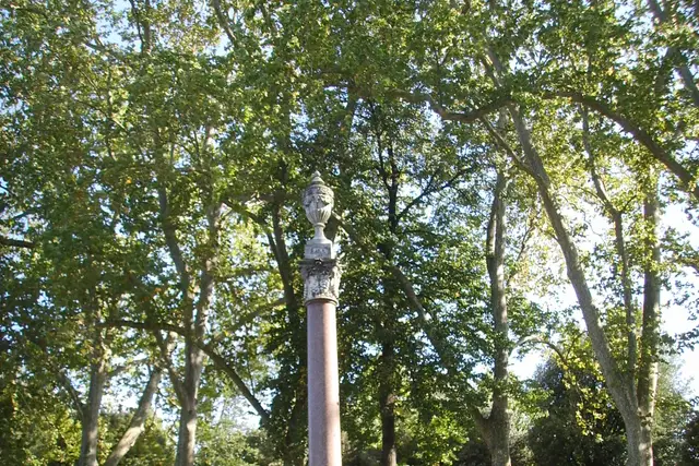 Una colonna di granito sormontata da un vaso, tra gli alberi
