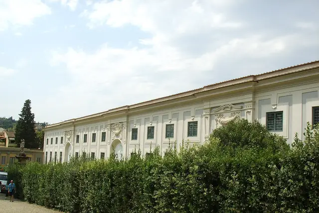 La lunga facciata della Limonaia, dietro una siepe